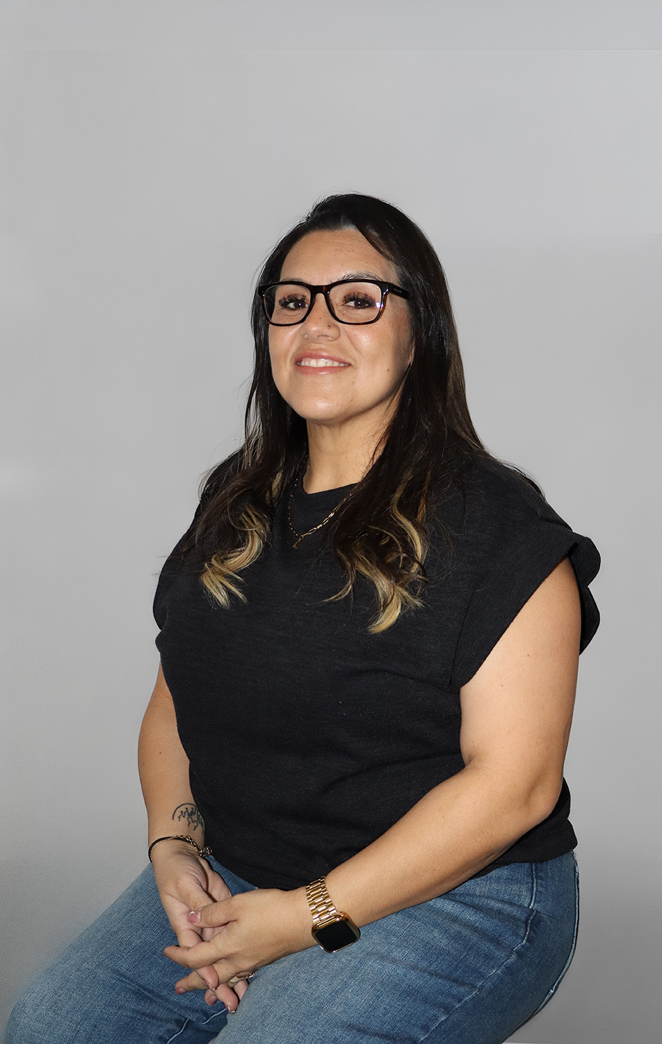 Jessica Gomez-Richardson, HR Administrator and AP Administrator at Asphalt Design, smiling at the camera wearing glasses against a neutral gray background